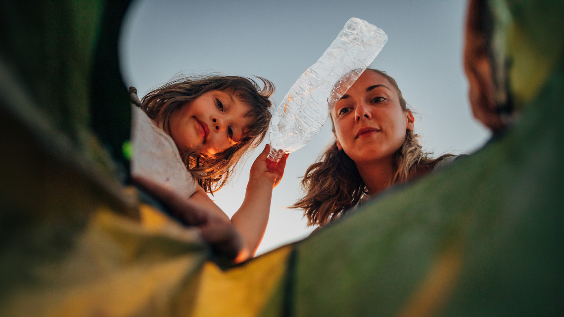Två yngre personer som källsorterar en plastflaska