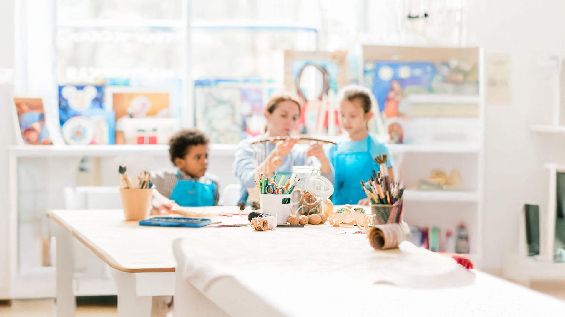Två barn som pysslar på en förskola tillsammans med förskolepedagog.