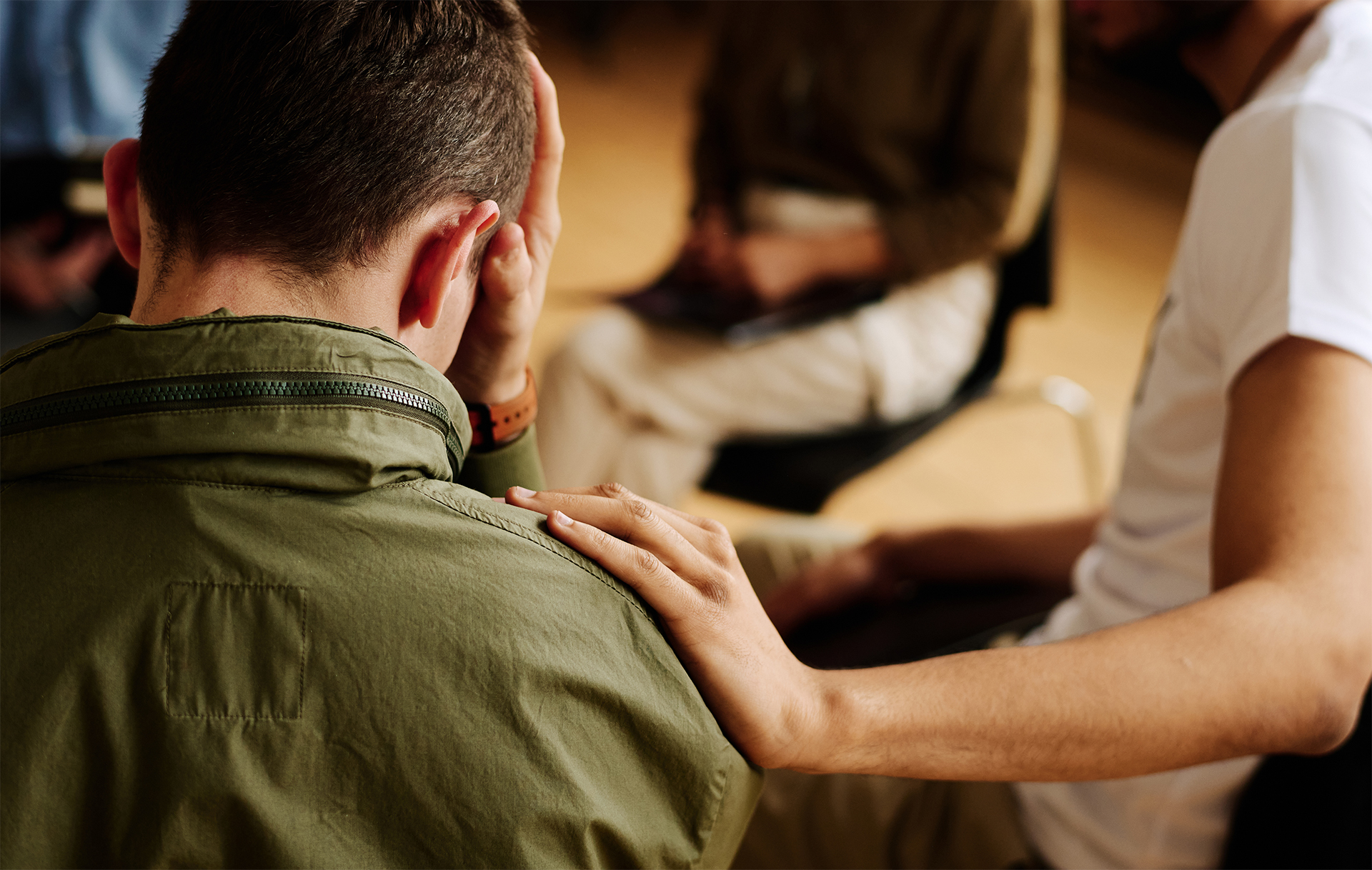 En person håller sin hand på en annans axel som för att trösta.